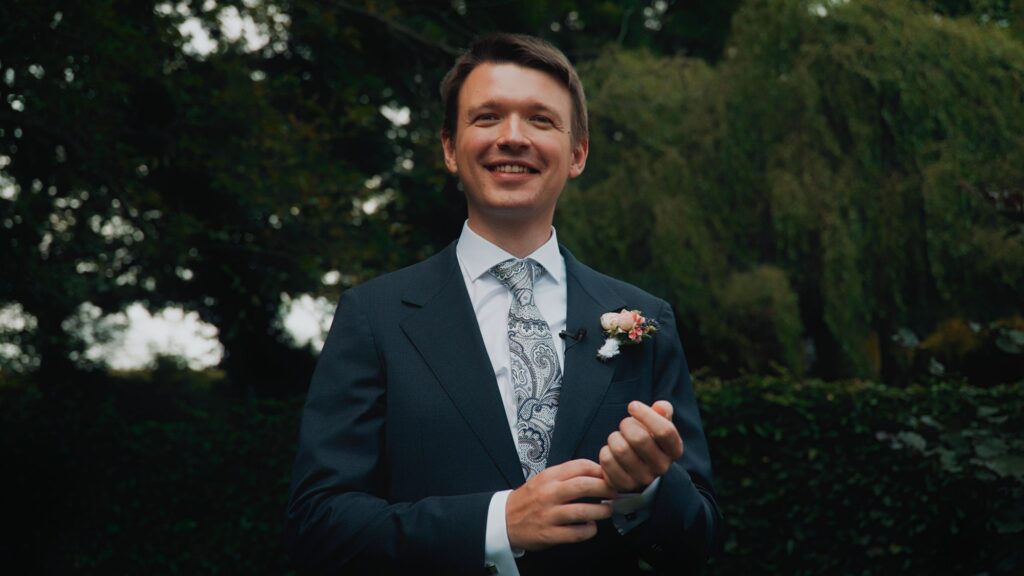 Uśmiechnięty pan młody w ogrodzie w dniu ślubu