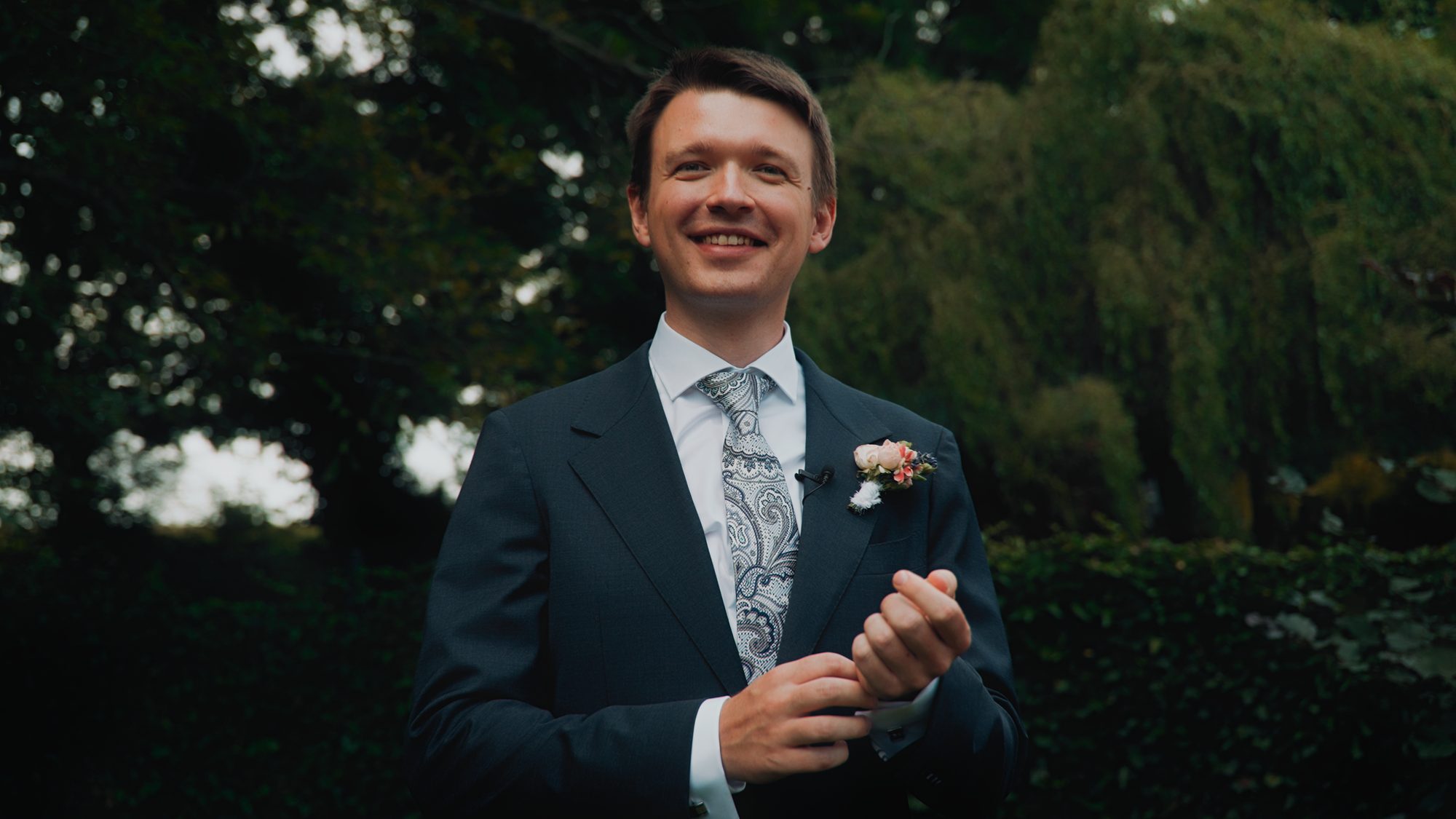 Uśmiechnięty pan młody w ogrodzie w dniu ślubu