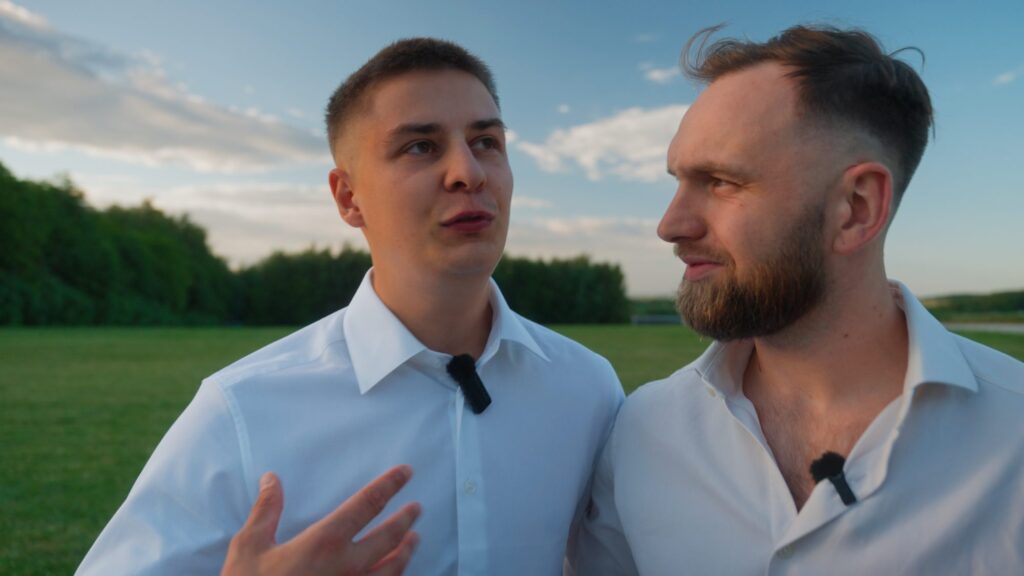 Wywiady ślubne: dwóch gości z mikroportami opowiada na łące